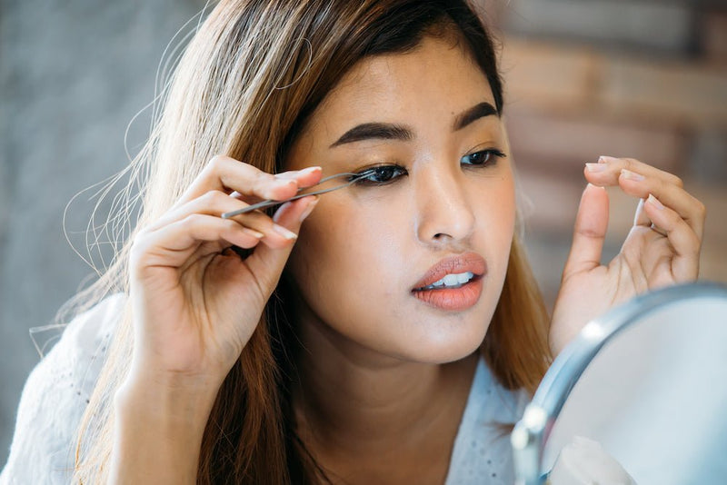 Asian woman applying false eyelashes